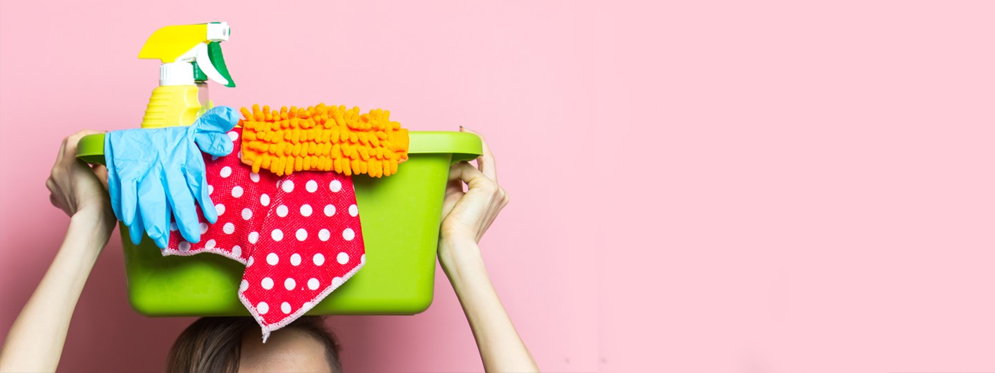 Person lifting a basket of cleaning supplies above their head. 