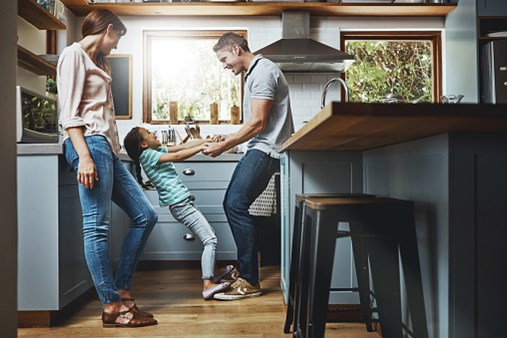 Family laughing and playing in a kitchen.