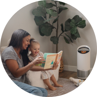 Mom and daughter reading a book together, laughing. 